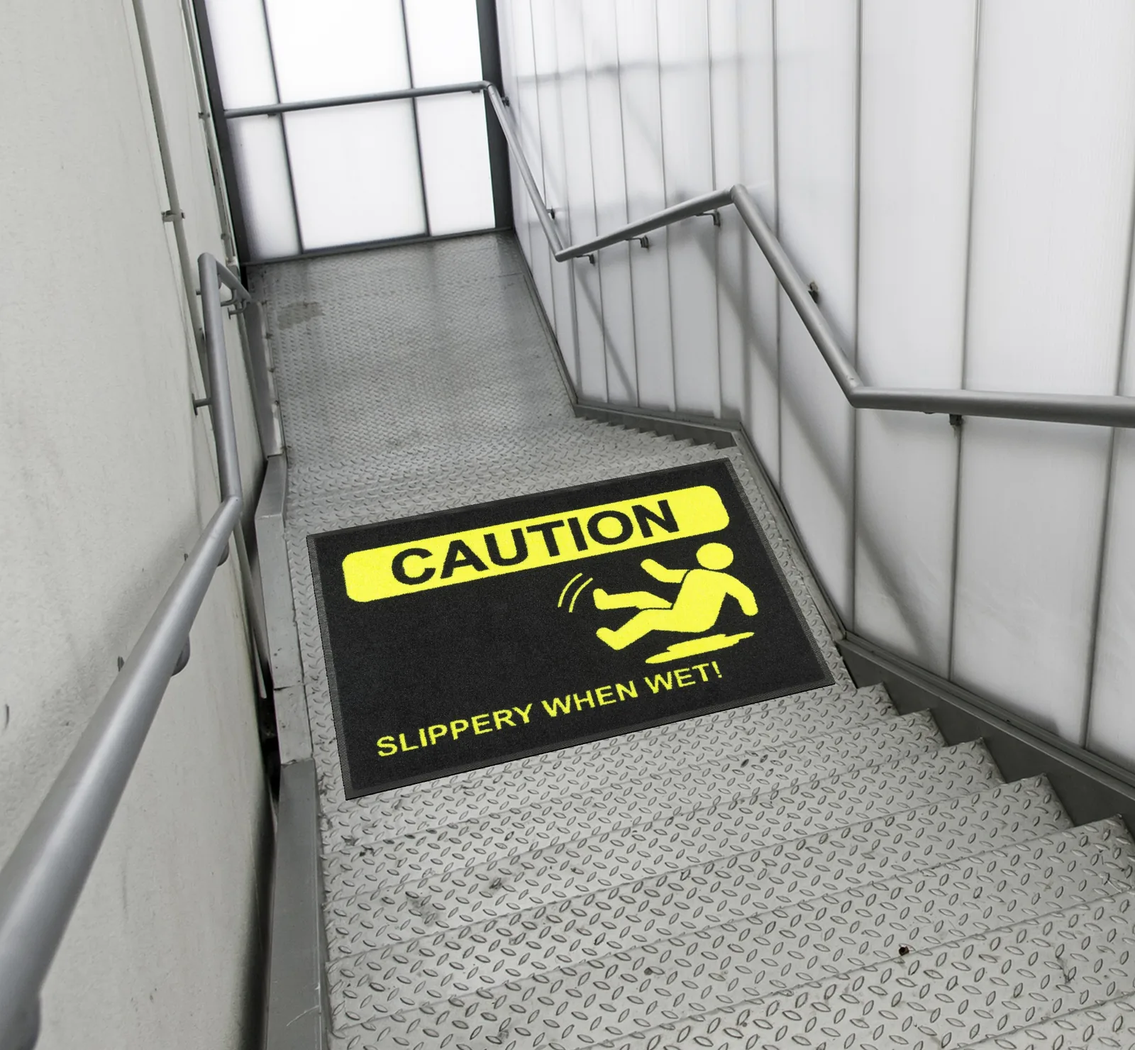 Čierna rohož JET PRINT HI-VIS so žltým symbolom pošmyknutia a nápisom CAUTION na schodiskovej podeste