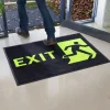 Čierna rohož JET PRINT HI-VIS so žltým nápisom EXIT a symbolom východu pri otvorených presklených dverách