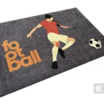 Sivá rohož JET PRINT LUMA s ilustráciou futbalistu, loptou a oranžovým nápisom