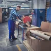 Pracovník na čiernej rohoži KLEEN COIL pri rezacom zariadení vo výrobnom priestore