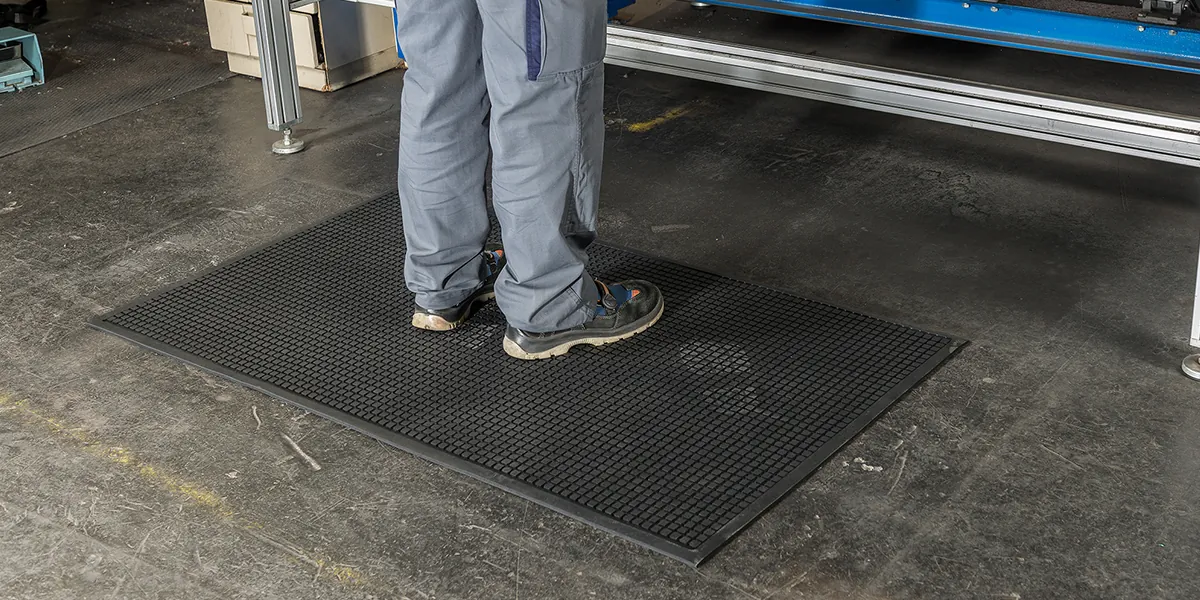 Detail pracovnej obuvi na čiernej profilovanej rohoži KLEEN CUSHION pri zariadení