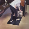 Žena stojaca na čiernej rohoži KLEEN CUSHION pri manipulácii s kovovým sudom za barom