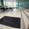 Čierna rohož KLEEN CUSHION na dlažbe vedľa mozaikových schodíkov v bazénovej hale