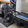 Pracovník stojaci na čiernej rohoži KLEEN CUSHION pri výrobnom stroji